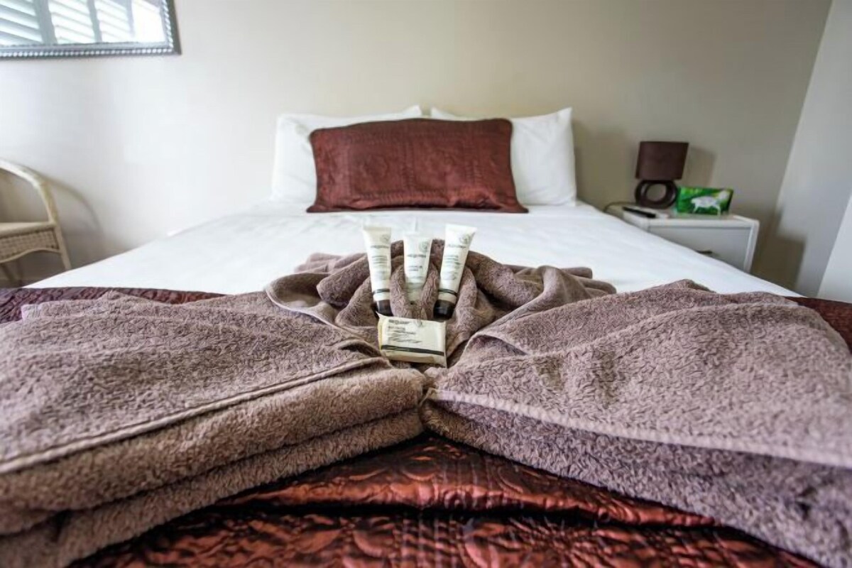 A neatly made bed with a brown blanket and a set of toiletries on the bed.