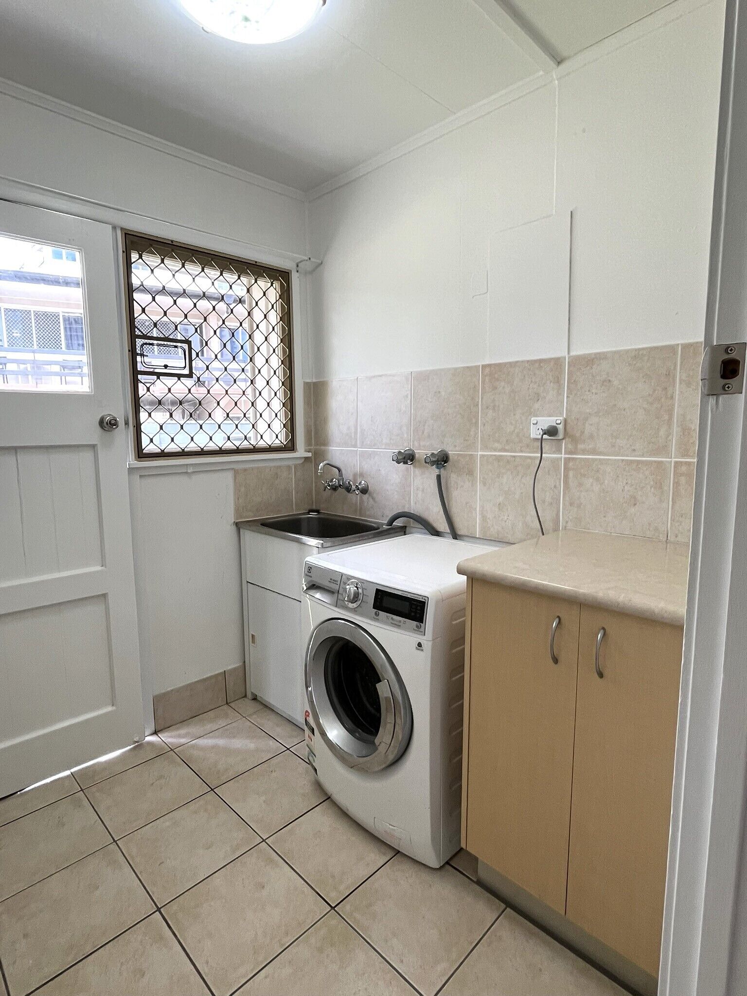 A compact laundry room with a washing machine, a sink, and a cabinet.