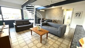 A modern living room with a sofa, a wooden coffee table, and a staircase leading to an upper level. - Tropicana Motel (Mermaid Beach)
