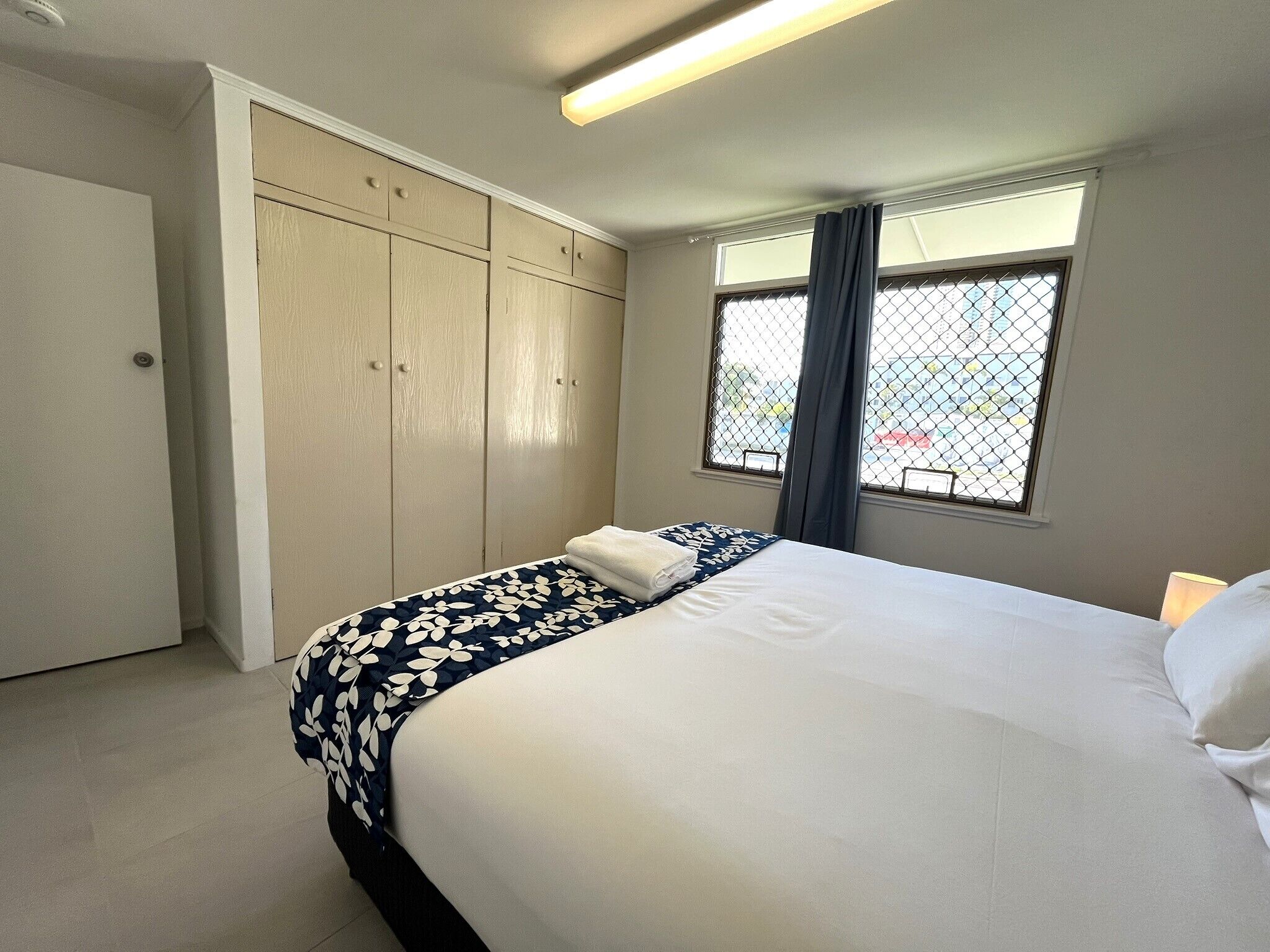 A bedroom with a bed, a wardrobe, a window with a view, and a ceiling light.