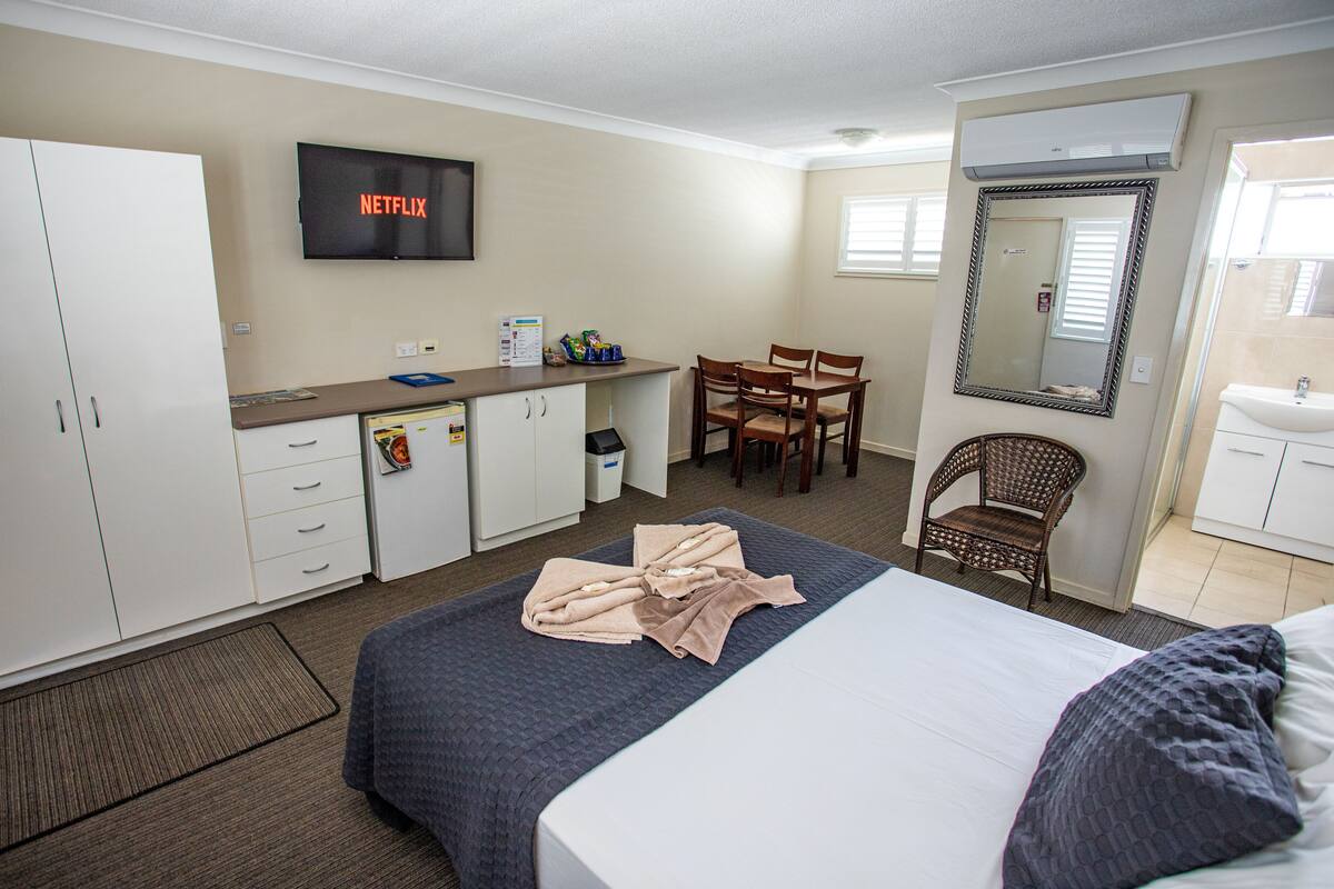 Ein Hotelzimmer mit Bett, Schreibtisch, Stuhl, Fernseher und Bad.