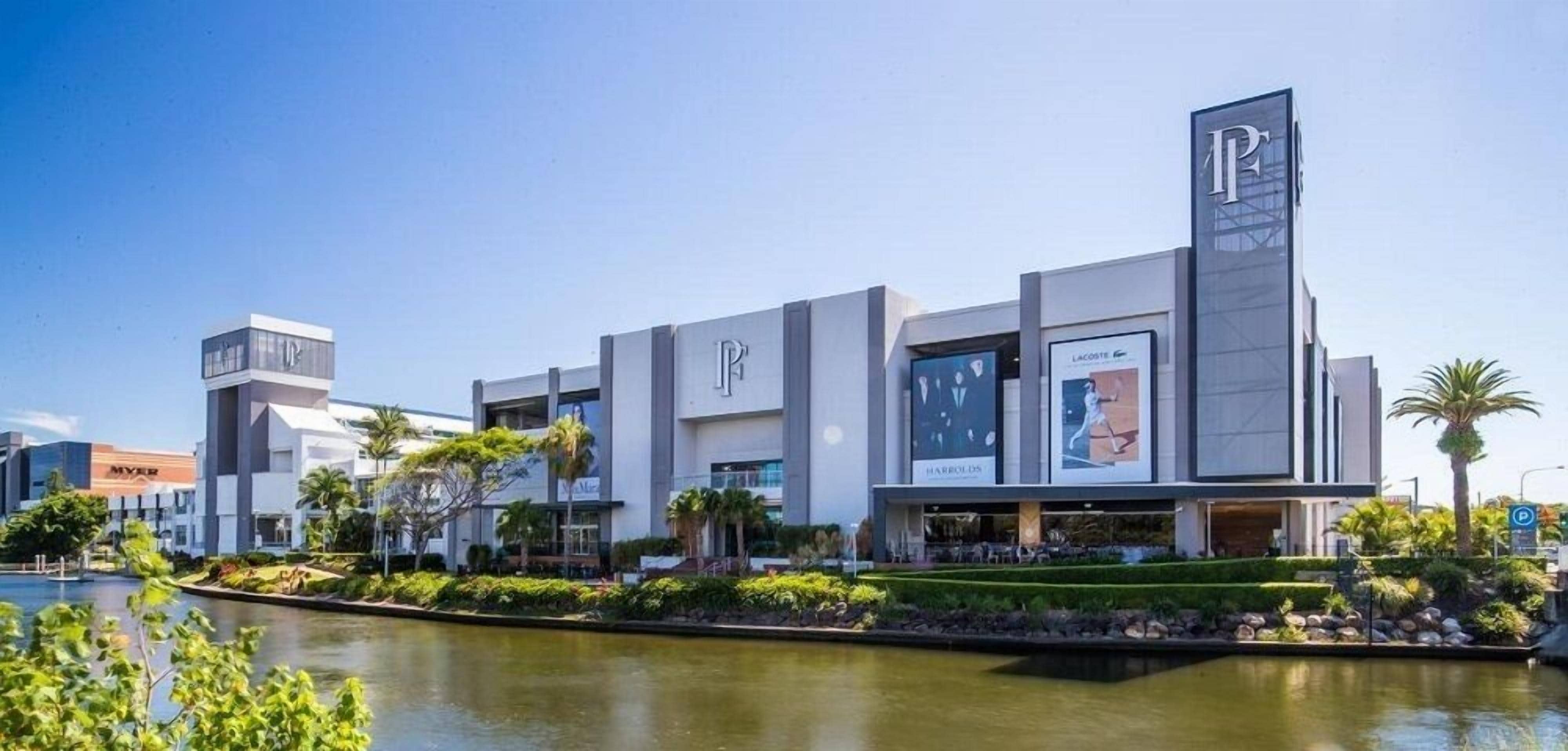 Un edificio moderno con un llamativo logo 'P', rodeado de vegetación y una fuente de agua.