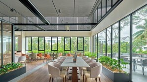 A modern meeting room with a long table, comfortable chairs, and large windows offering a view of greenery and buildings. - Four Points by Sheraton Johor Bahru (Masai)