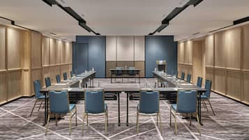 Un salón de conferencias con una mesa larga, sillas y una pequeña mesa con una lámpara.