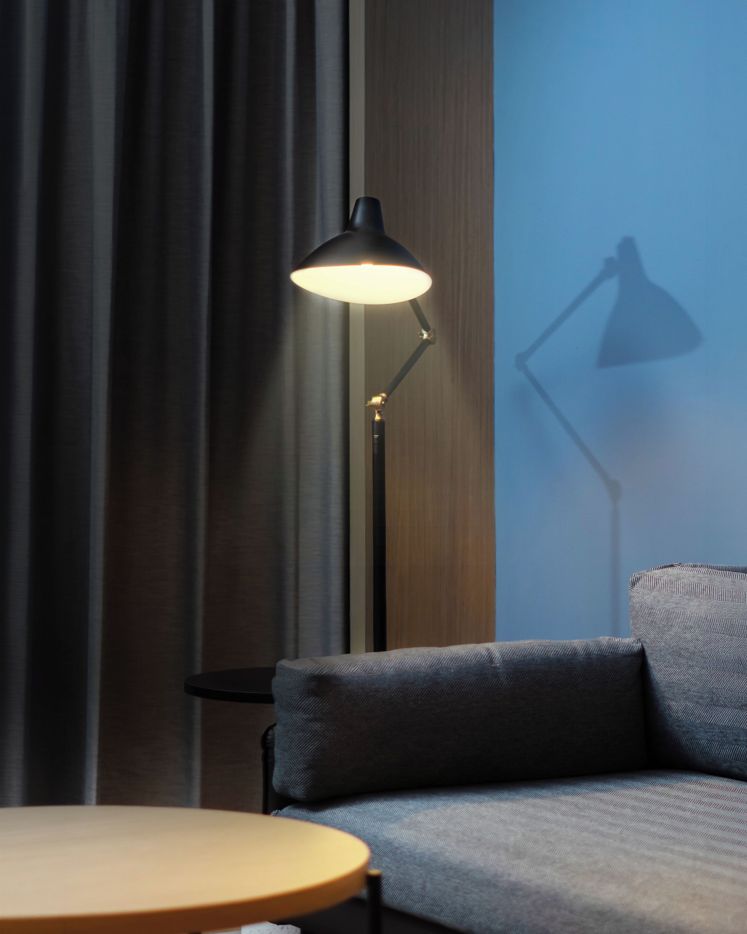 A modern room with a sofa, a small round table, and a floor lamp.