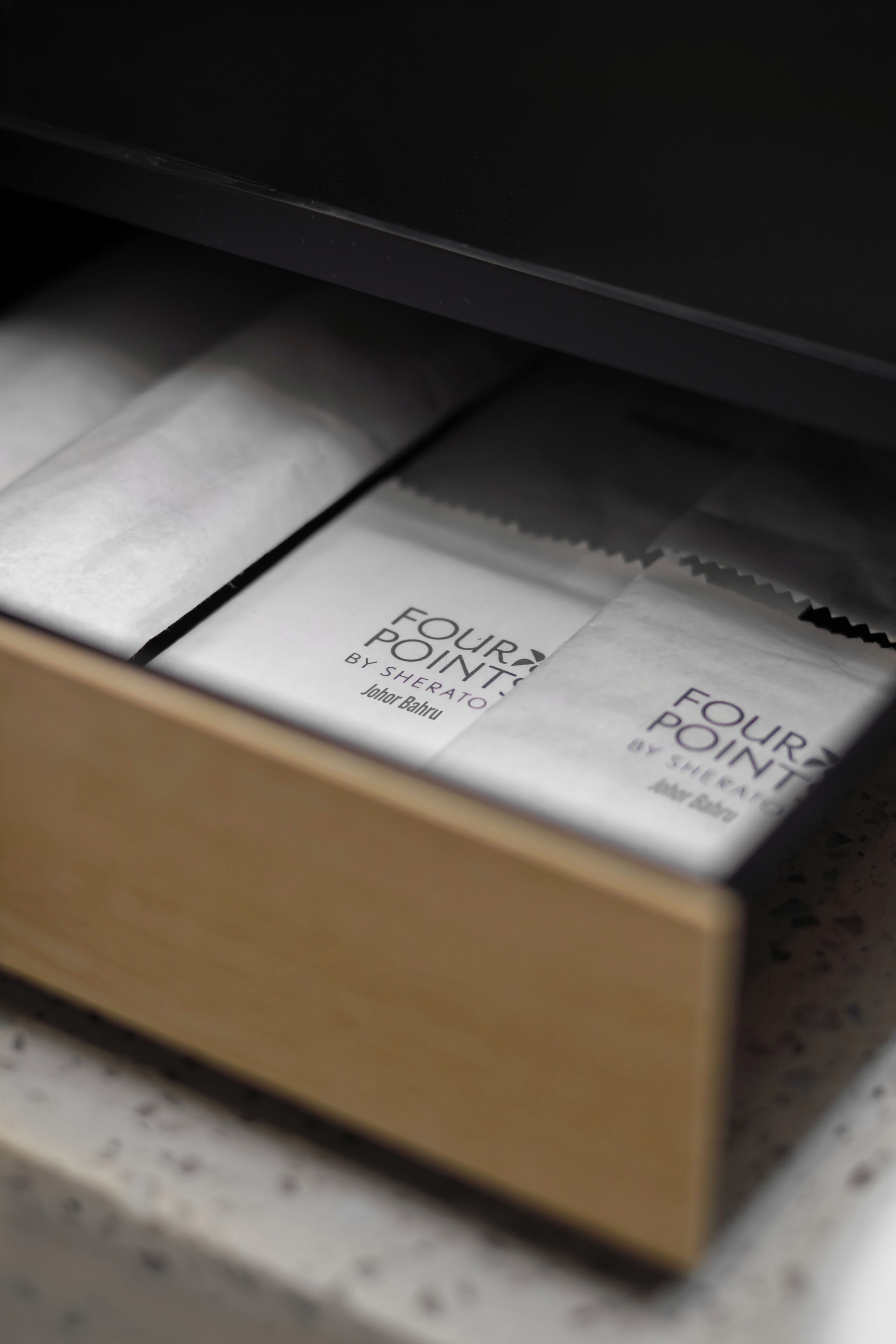 A drawer with multiple compartments containing white boxes labeled 'FOUR POINT BY SHERATO JOHOR BAHRU.'