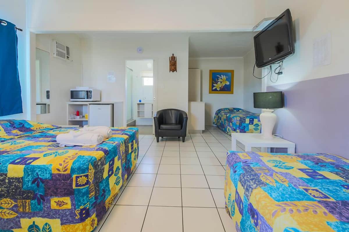 A hotel room with two beds, a TV, a desk, and a chair.