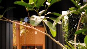 A modern building with a glass entrance, a wicker seating area, and lush greenery. - The Hide Byron Bay (Byron Bay)