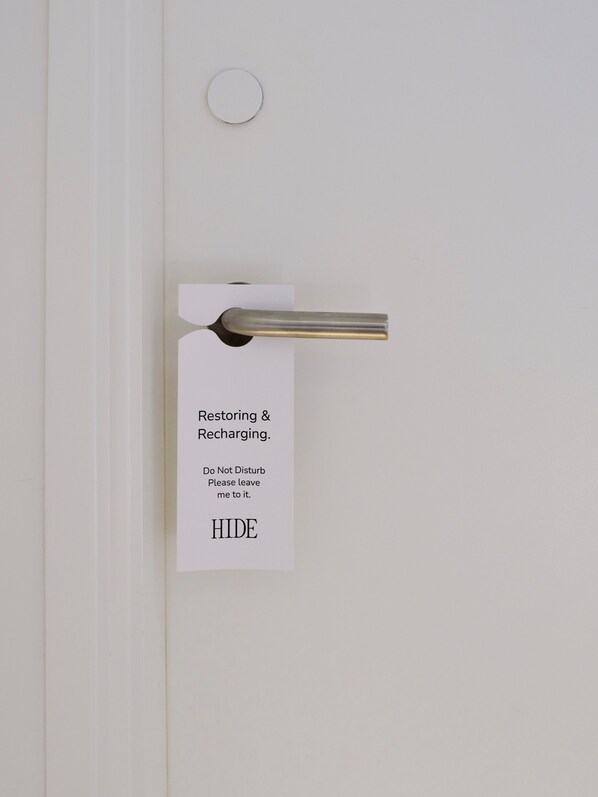 Eine Tür mit einem Metallgriff und einem Schild mit der Aufschrift 'Wiederherstellung & Aufladung. Bitte nicht stören. Lassen Sie mich in Ruhe. HIDE'.