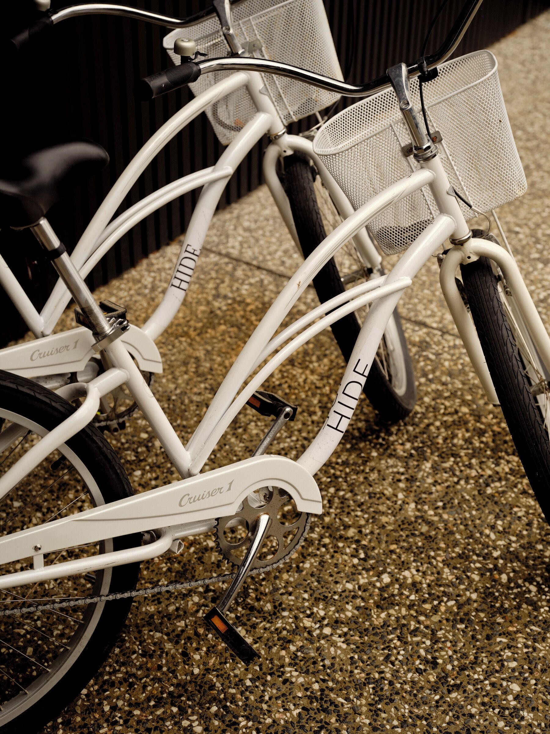 Una bicicleta blanca con la marca 'Cruiser 1', una canasta y una cadena.