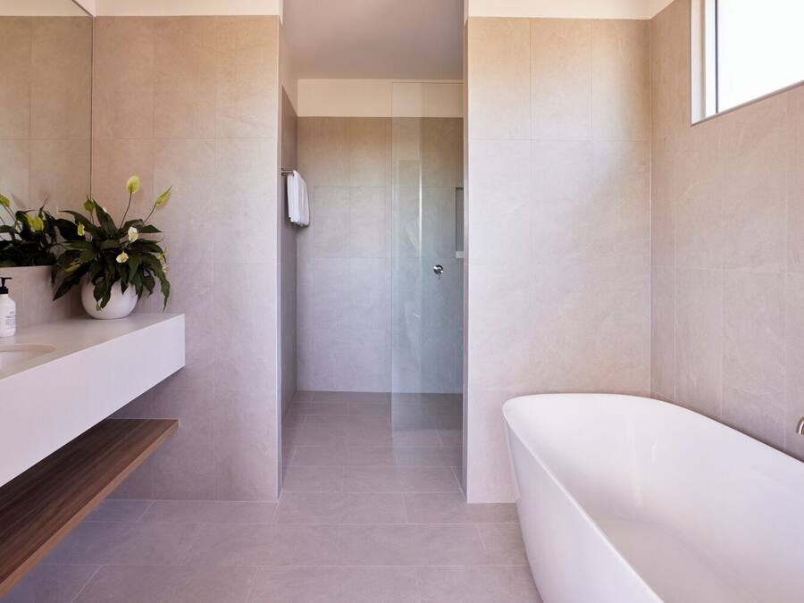 Un baño moderno con una bañera blanca, un tocador con espejo y una planta en maceta.