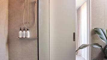 Un baño moderno con cabina de ducha de vidrio, una puerta blanca y una planta en maceta.