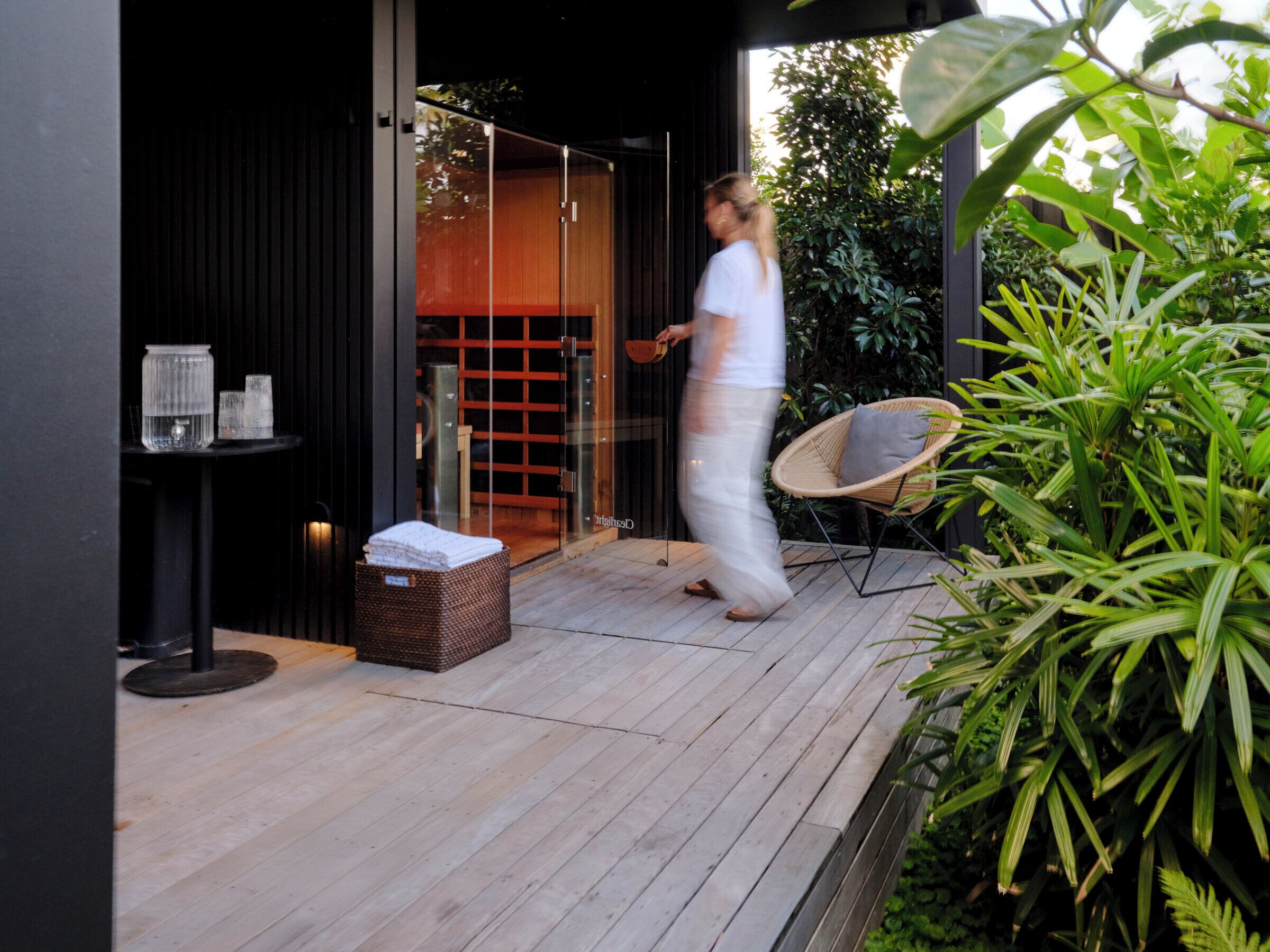 A wooden deck with a wicker chair, a small table with glasses, and a basket.