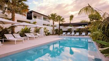 Relax by the serene pool surrounded by lush tropical plants and modern architecture.