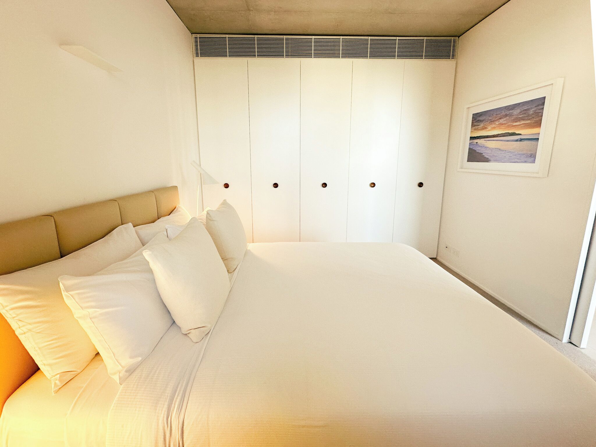 A bedroom with a large bed, a headboard, and a wardrobe with multiple doors.