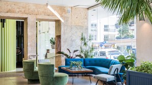 A modern lobby with a blue sofa, green armchairs, and a coffee table. - Hotel Ravesis (Bondi Beach)