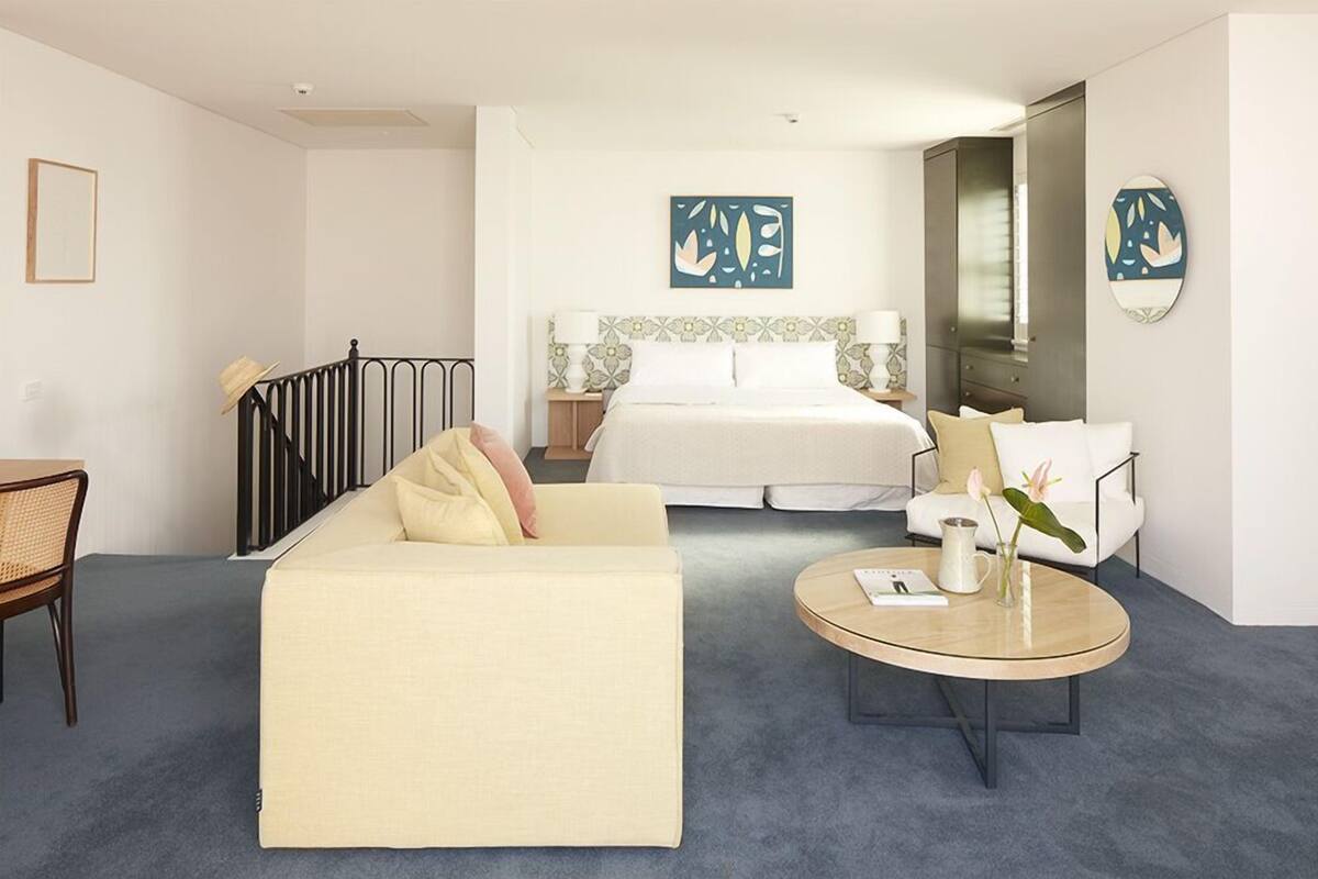 A hotel room with a bed, a sofa, a coffee table, and a chair.