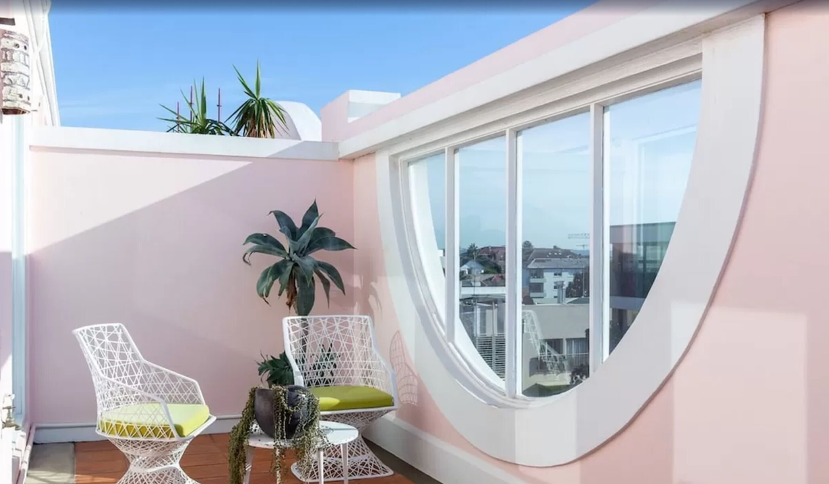 Un balcon avec deux chaises en osier blanches, une petite table ronde et une plante en pot.