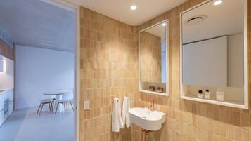 A modern bathroom with beige tiles, a white sink, and a large mirror.