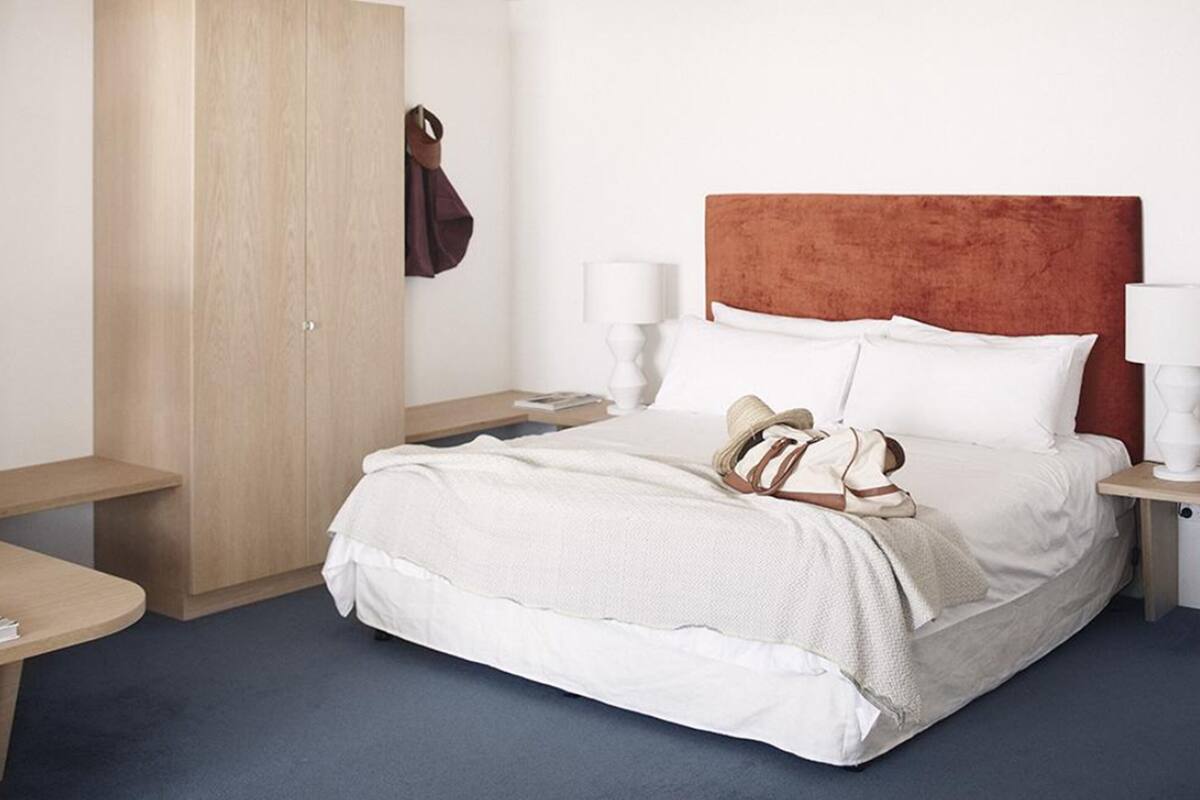 A hotel room with a bed, bedside tables, a wardrobe, and a desk.