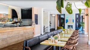 A restaurant with a bar area, seating with cushions, and potted plants. - Hotel Ravesis (Bondi Beach)