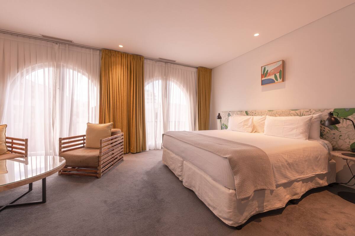 A modern hotel room with a large bed, a round table, and a sofa.