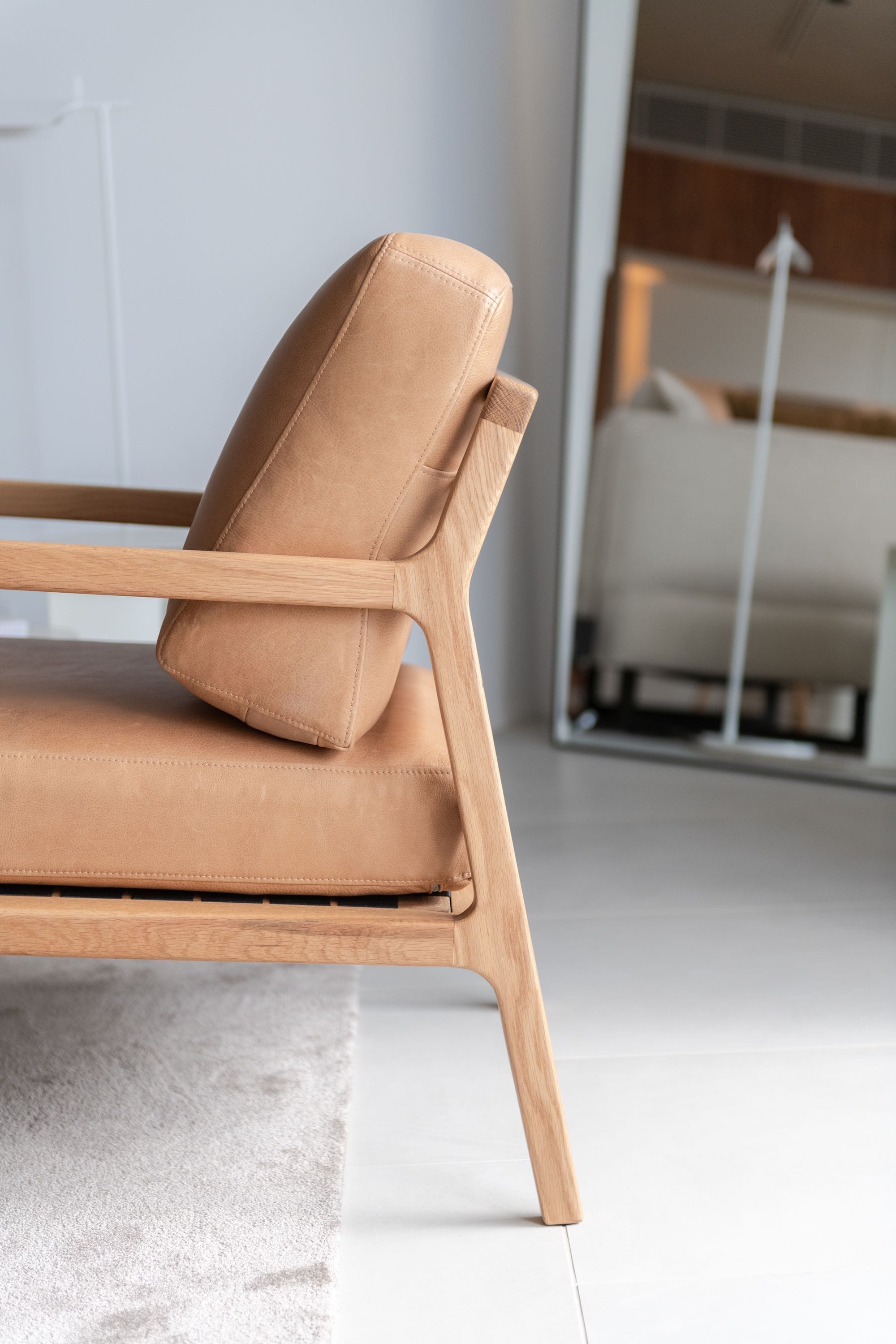 A modern chair with a wooden frame and a tan cushion.