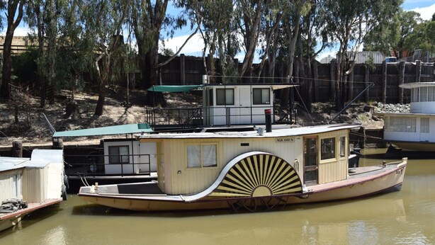 A houseboat docked at a pier with a covered deck area and a small cabin structure. - Big River Motel (Echuca)