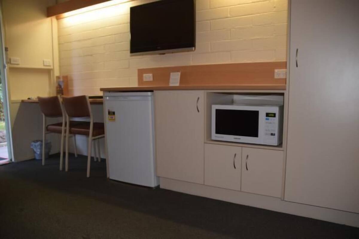 A kitchenette with a microwave, a small refrigerator, and a chair.