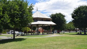 A gazebo with a conical roof, surrounded by grass and trees, with a building labeled "Museum" in the background. - Big River Motel (Echuca)