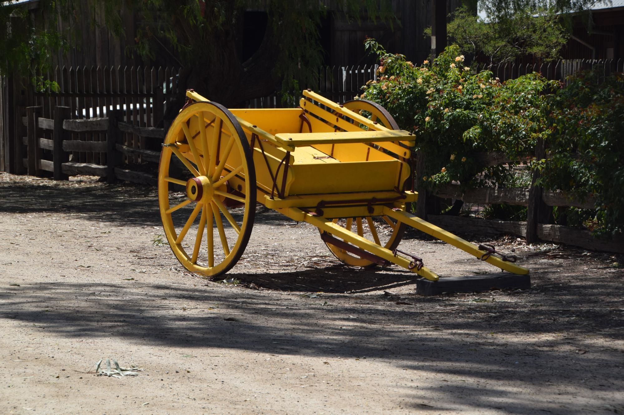 Une voiture jaune avec de grandes roues, garée sur un chemin de terre.