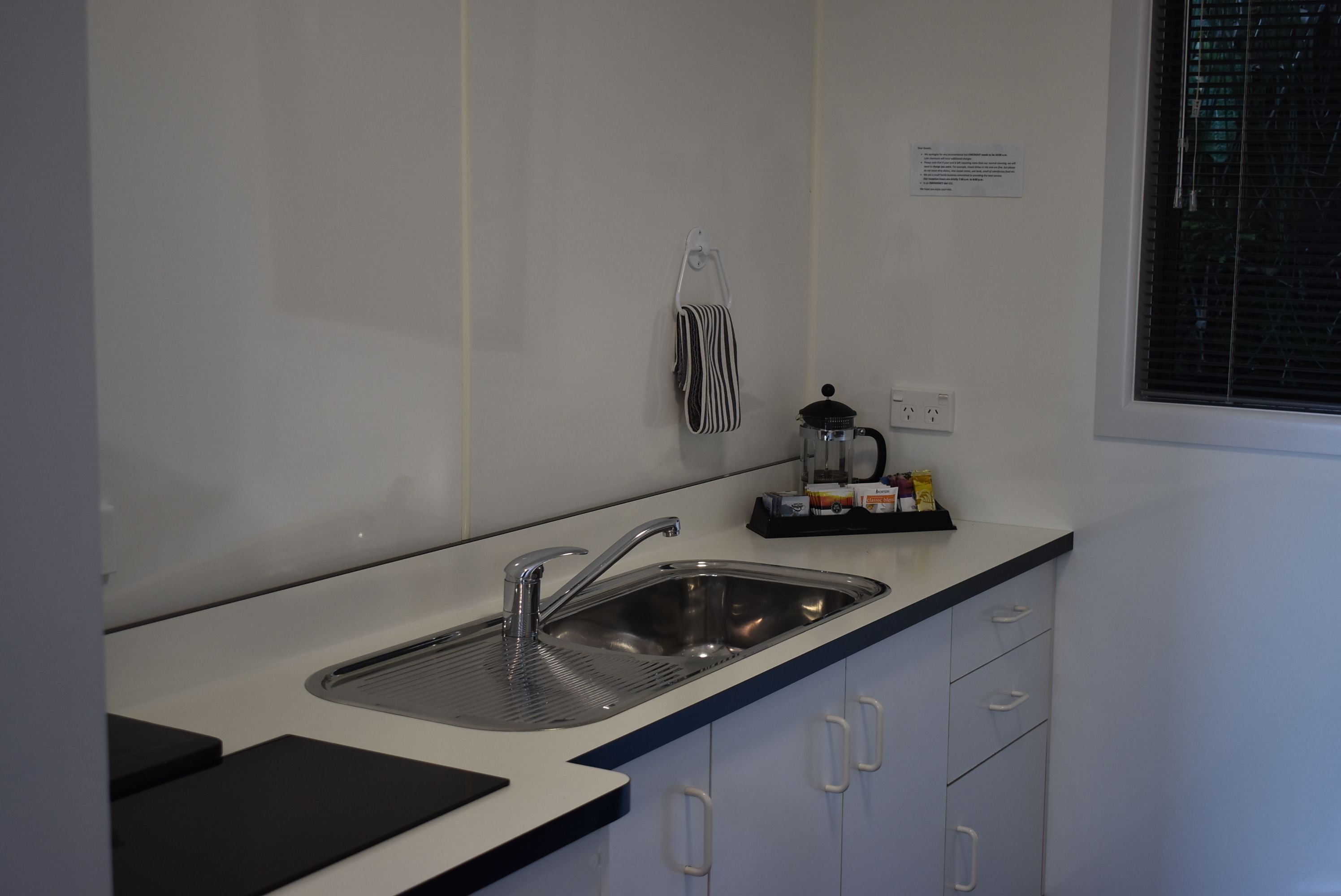 A modern kitchen with a stainless steel sink, a kettle, and a coffee maker on the counter.