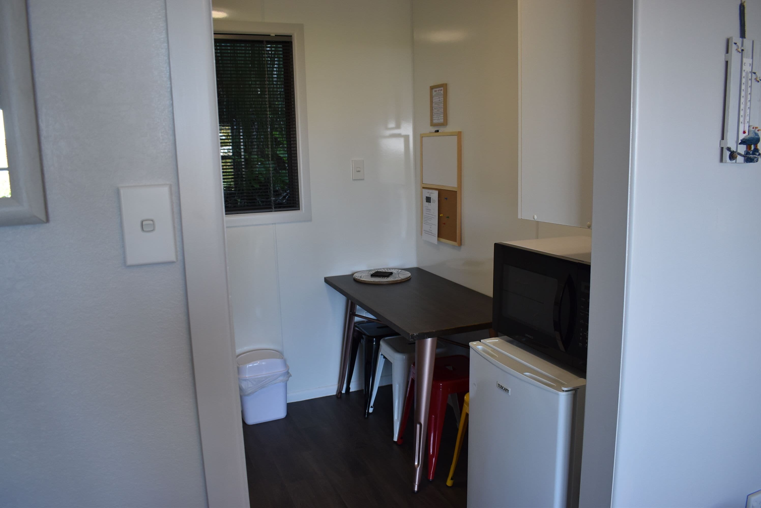 A compact kitchen with a refrigerator, microwave, and a small dining table.