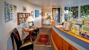 A reception area with a wooden desk, a lamp, a map on the wall, and travel brochures.