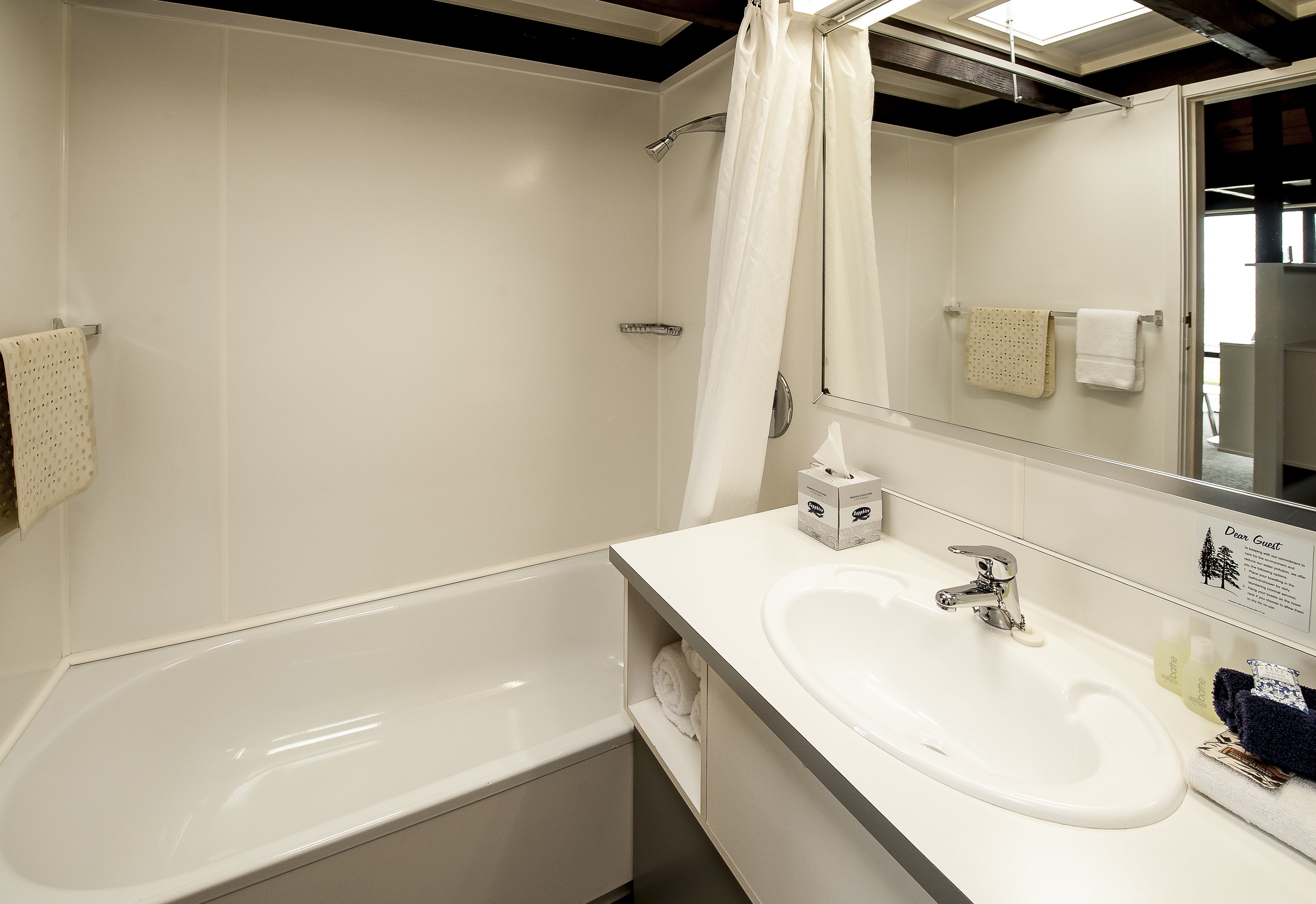 Une salle de bain moderne avec une baignoire blanche, un lavabo et un rideau de douche.