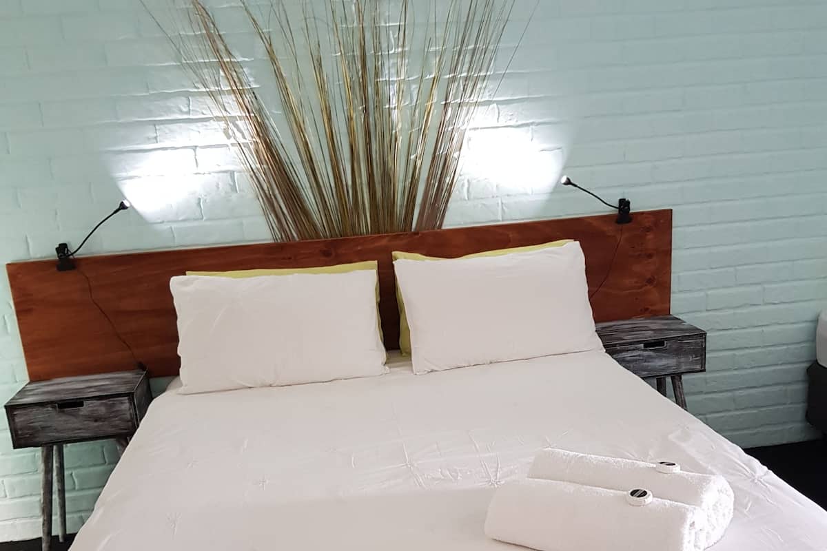 A neatly made bed with white linens and a wooden headboard, flanked by two bedside tables with lamps.