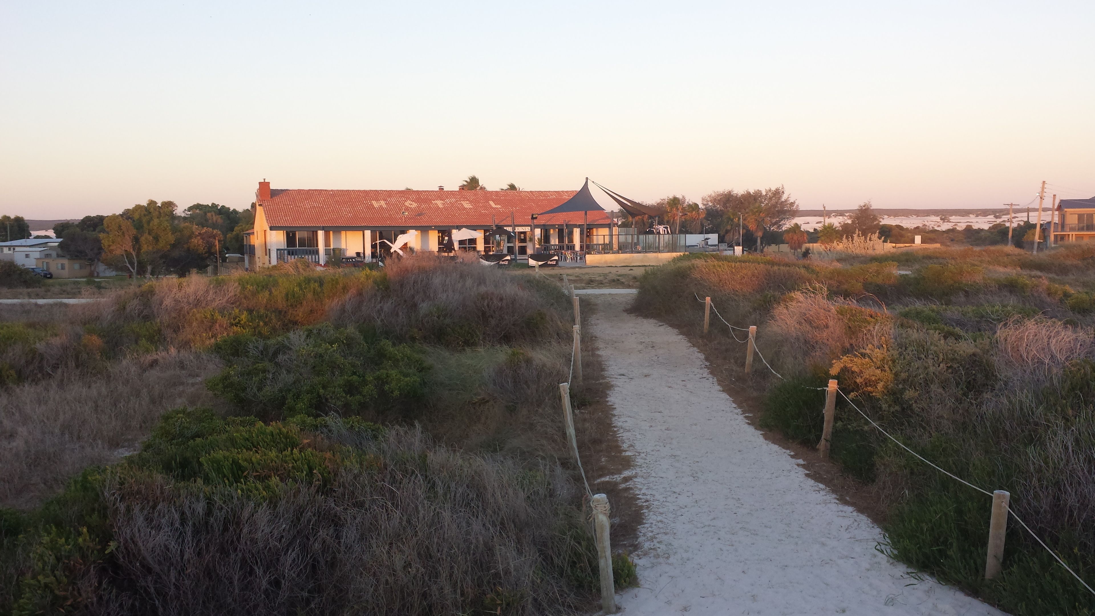 A building with a red-tiled roof, a pathway leading to it, and surrounding vegetation.