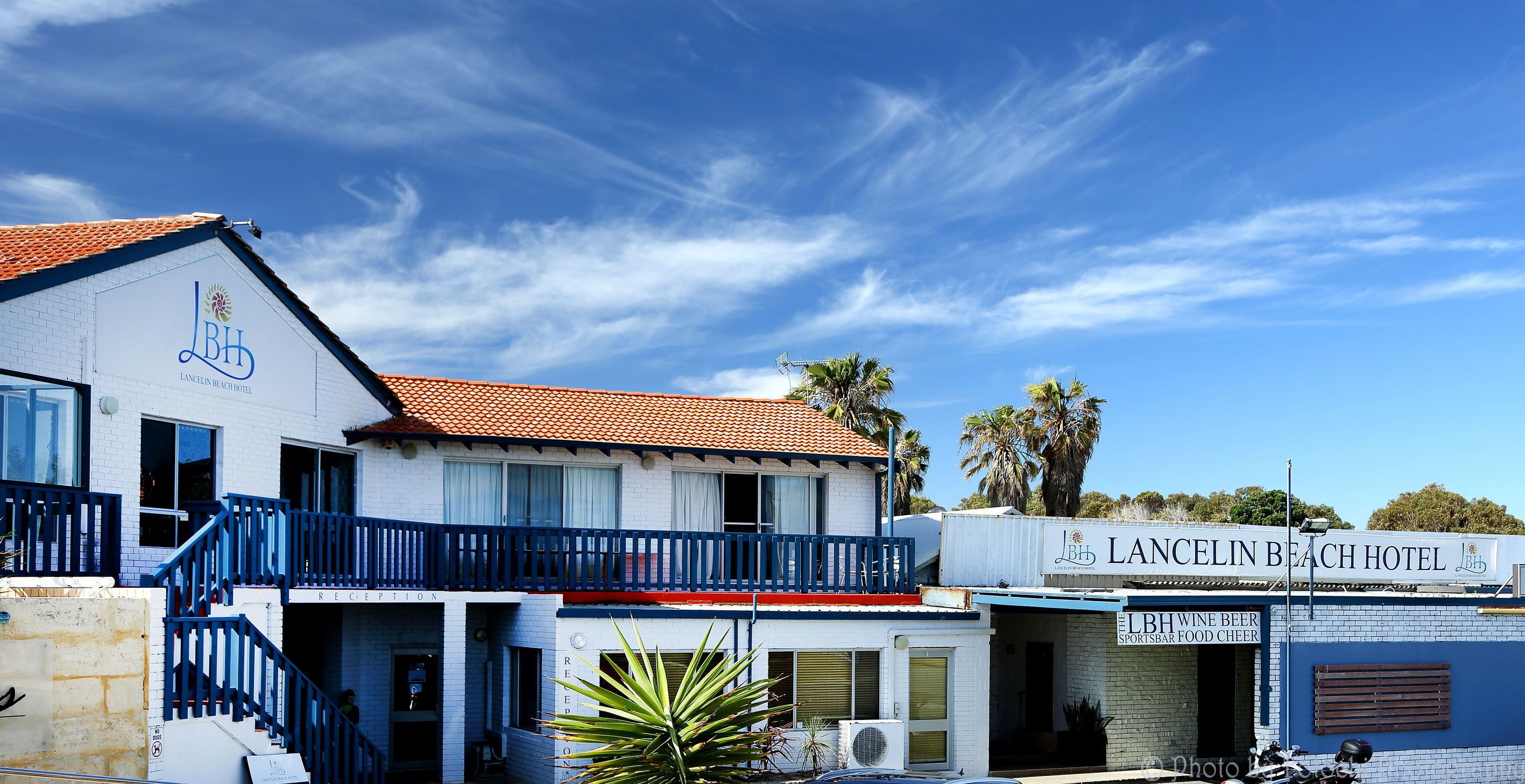 Un hôtel doté d’une réception, d’un balcon et d’une enseigne indiquant : « LBH, bar proposant des vins, des bières, des plats, et diffusant des événements sportifs ».