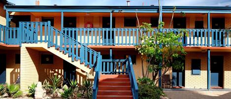 Un motel de varios pisos con una escalera central, asientos al aire libre y fachada de ladrillo.