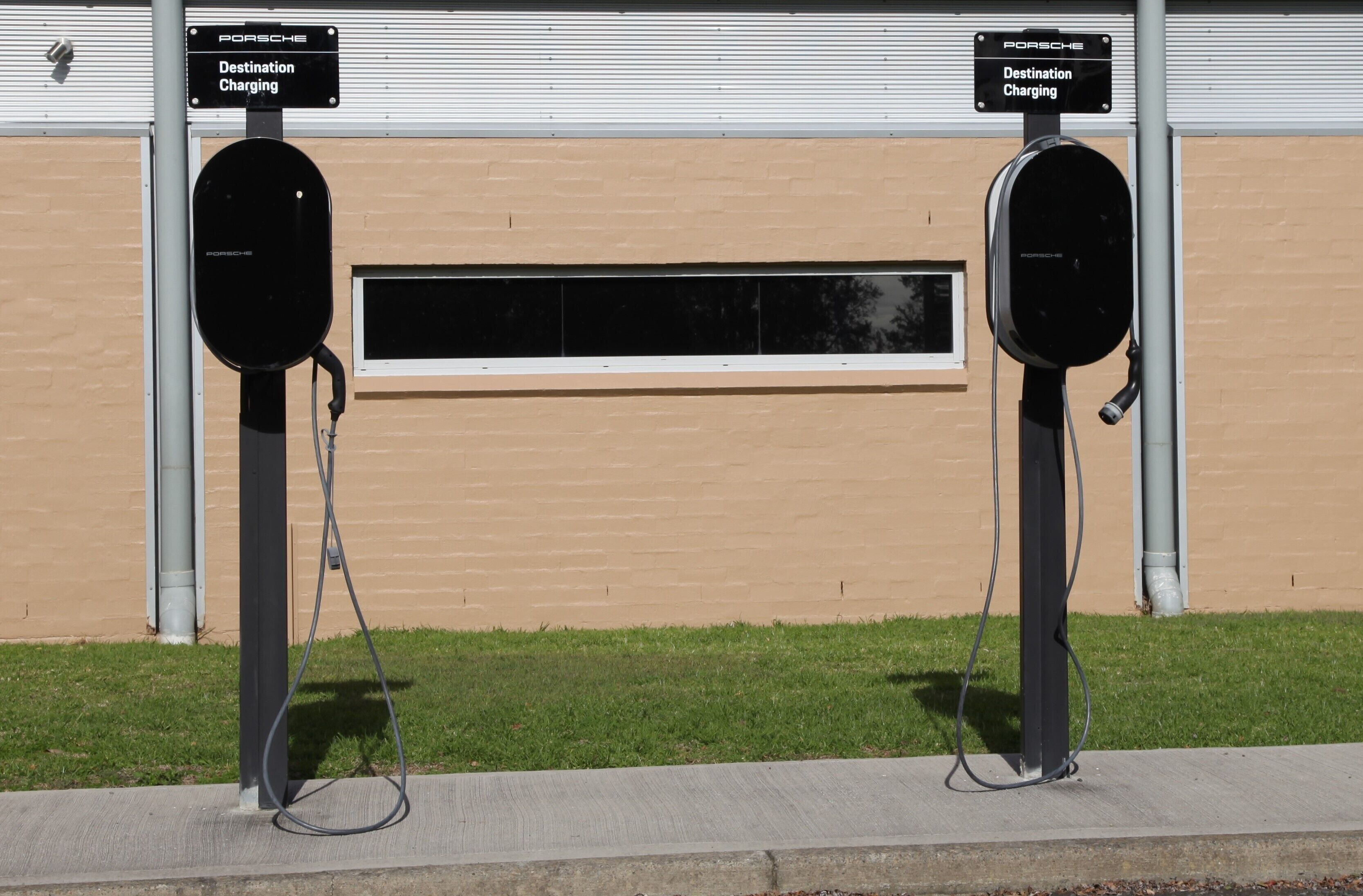 Two Porsche Destination Charging stations with a building in the background.