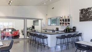 Een moderne keuken met een bar, een groot raam en een rode sportauto zichtbaar door de glazen deur.