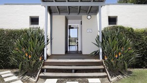 Een gebouw-ingang met een overdekte veranda, een bord met de tekst 