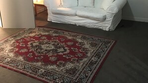 A white sofa, a red and beige patterned rug, a lamp, and a framed picture on the wall.