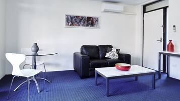 Una sala de estar moderna con una mesa de vidrio, un sofá de cuero negro y una silla blanca.