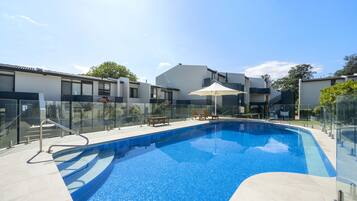 Una piscina al aire libre, sillones reclinables de piscina