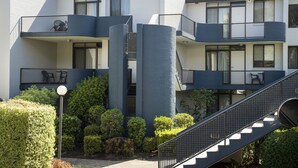 Un edificio de apartamentos moderno con varios balcones, una estructura cilíndrica central y una escalera que conduce a los pisos superiores.