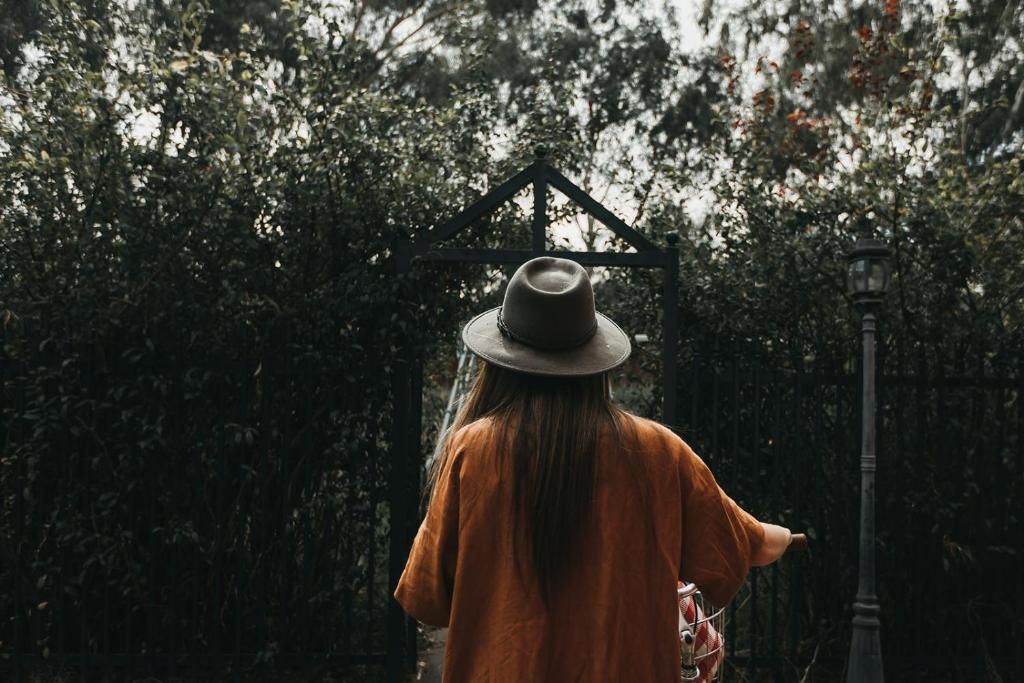 Une personne se promène dans un jardin, on y voit une porte en métal et un lampadaire.