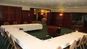 A conference room with two long tables, chairs, and a small table with a chair.