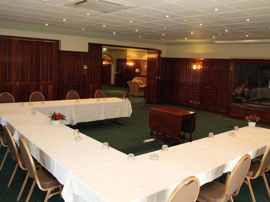 A conference room with two long tables, chairs, and a small table with a chair.