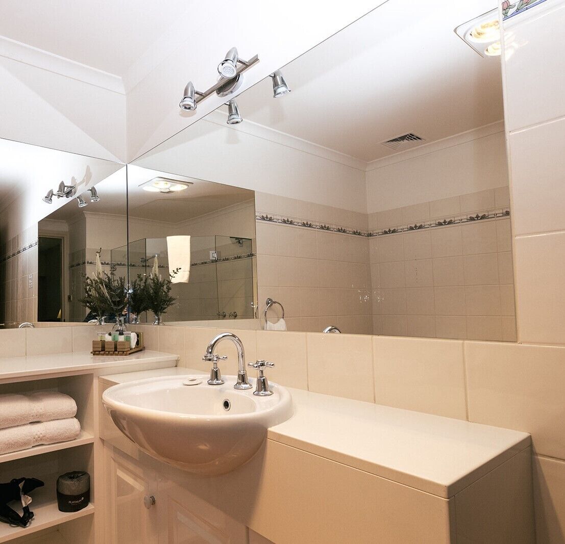 A modern bathroom with a large mirror, a sink, and a shower area.
